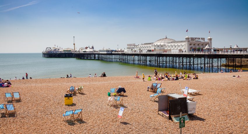 BRIGHTON, UK - JUN 5, 2013: Holidayers enjoying good summer weather at shingle beach near the Brighton Palace Pier